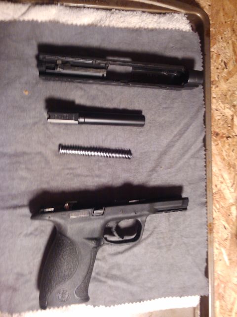 1989 Ford Bronco - The components of a handgun are arranged on a gray cloth, ready for cleaning or reassembly.