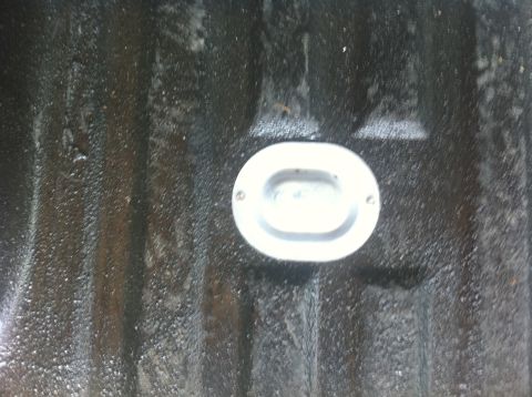 1990 Ford Bronco - Close-up of an oval tie-down anchor installed in a truck bedliner.