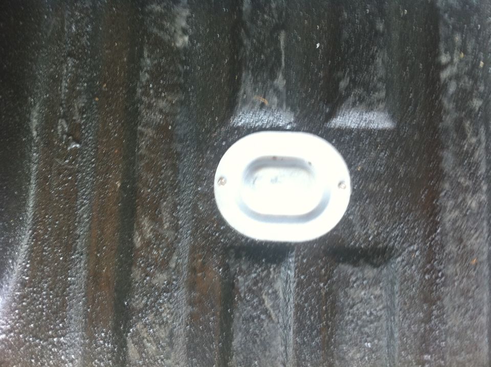 Oval tie-down anchor in a dark, ribbed truck bedliner