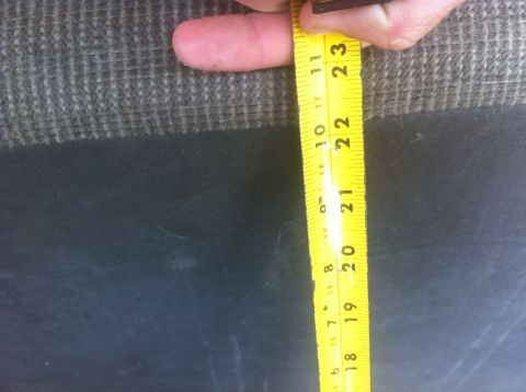 1990 Ford Bronco - A yellow measuring tape is used to measure a dark, textured surface, with markings visible from 20 to 23 inches.