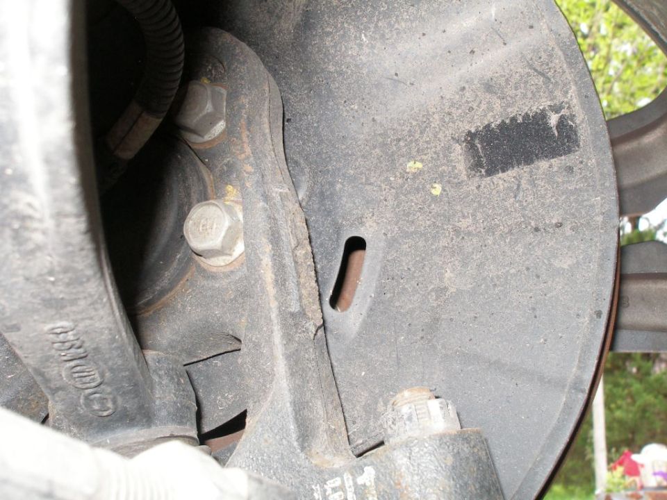 Close-up of a vehicle's brake dust shield with suspension components visible