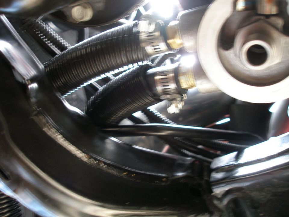 Close-up of two black corrugated hoses connected to a silver fitting, likely part of an oil cooling system