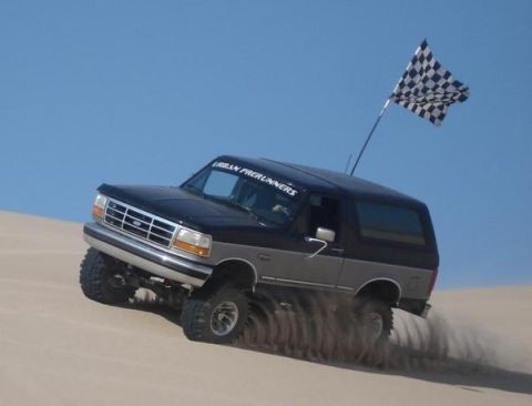 1995 Ford Bronco - This 1995 Ford Bronco is shown off-roading in the sand dunes with a checkered flag flying.