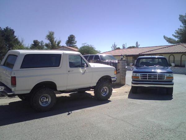 White 1995 Ford Bronco and blue Ford F-150 parked in driveway