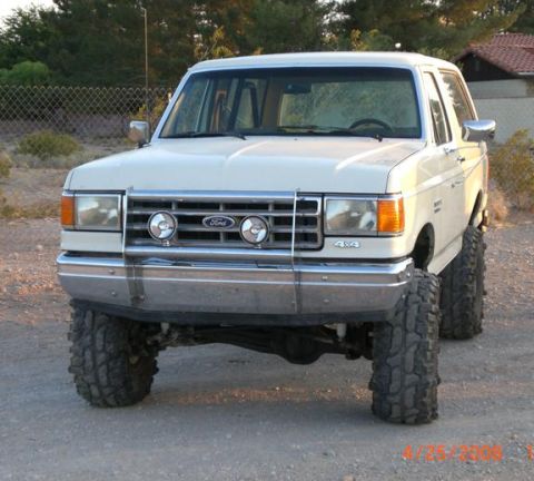 1995 Ford Bronco - This lifted Ford Bronco features oversized tires and a prominent grille with auxiliary lights.