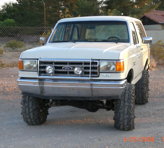 White Ford Bronco with lifted suspension and large tires, front view