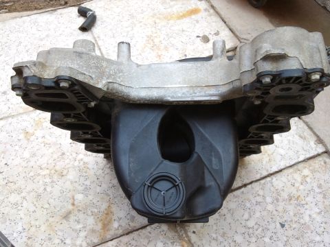 1998 Ford Crown Victoria - Engine intake manifold part shown from above, with a black hose nearby.