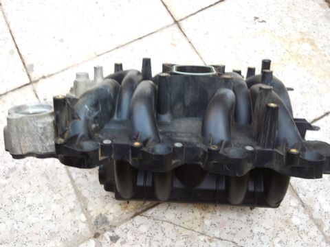 1998 Ford Crown Victoria - A black plastic intake manifold with a silver metal component is shown from a side angle on view.