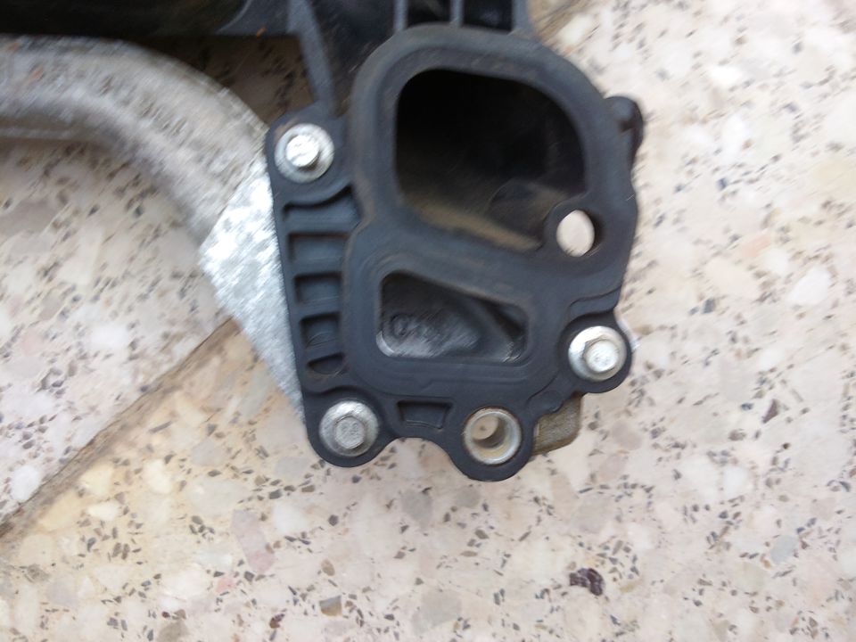 Close-up of a black plastic intake manifold gasket attached to a metal pipe