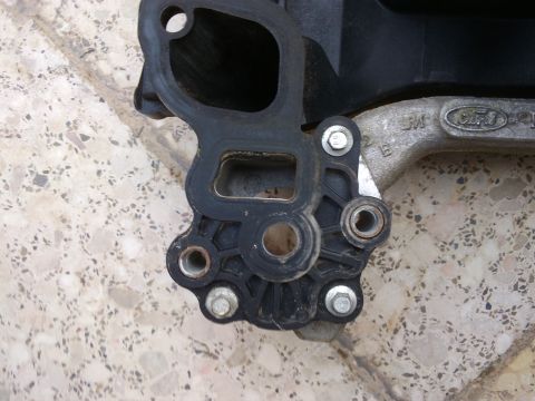 1998 Ford Crown Victoria - Close-up of a Ford intake manifold part, showing the Ford logo stamped on the metal component.