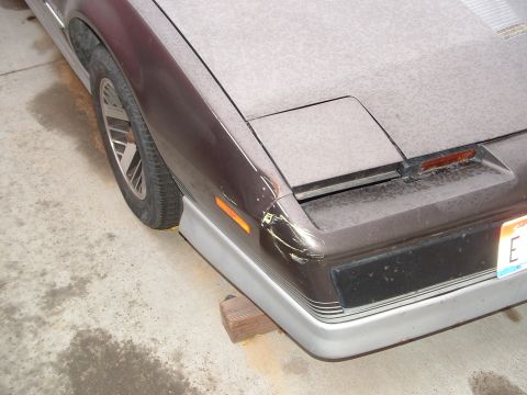 1985 Chevrolet Camaro - A brown car with a silver lower bumper is shown from the front right, with visible damage to the fender and bumper.