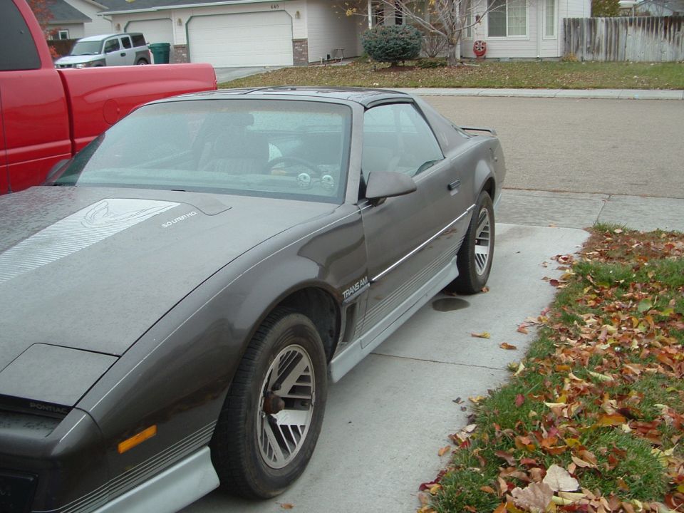 Gray 1985 Pontiac Trans Am parked next to a red truck