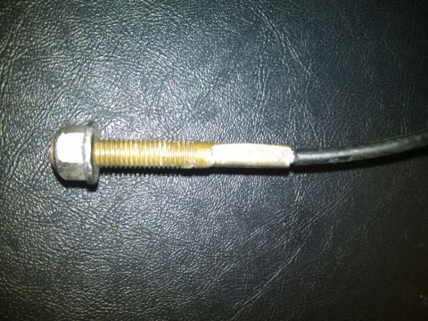 1993 Ford Bronco - Close-up of a bolt and cable assembly against a textured dark background.