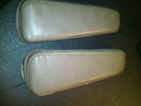 1993 Ford Bronco - Two tan leather armrests are shown, likely interior car parts, with visible stitching and rounded edges.