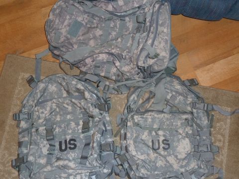 1992 Ford Mustang - Three US military backpacks are laid out on a floor. Two have 'US' printed on them.