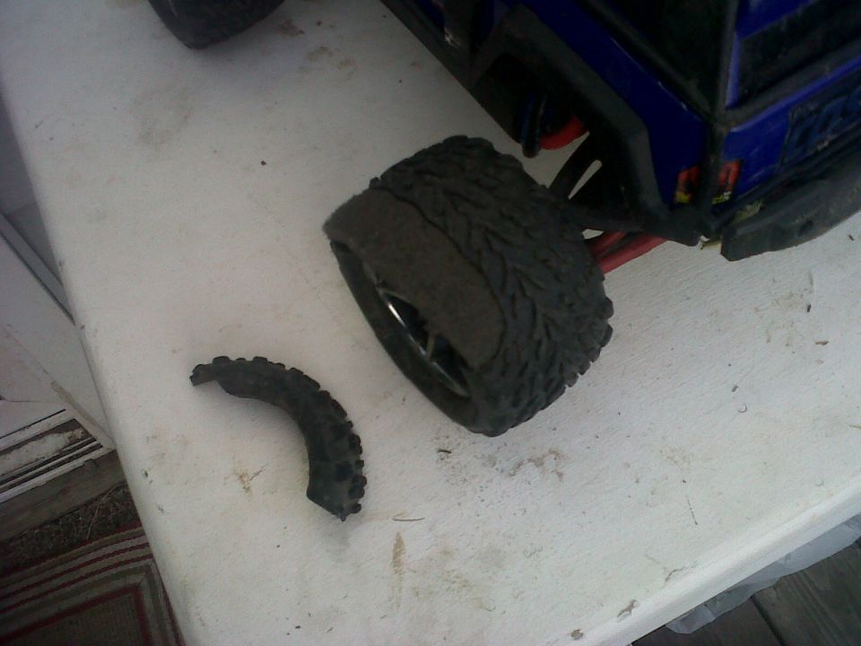 RC car tire with a chunk missing, sitting next to the wheel
