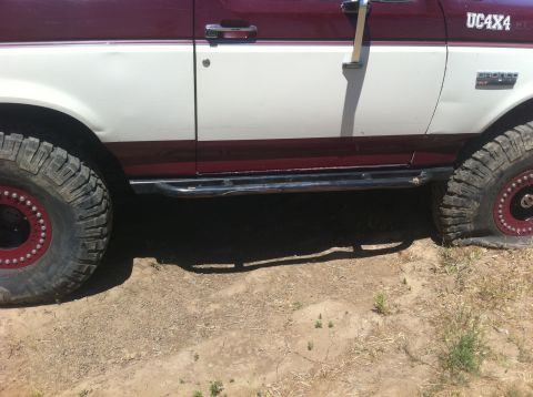 1990 Ford Bronco - This 1990 Ford Bronco features a two-tone red and white paint scheme, off-road tires, and protective side steps.