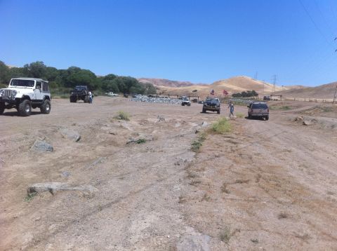 1990 Ford Bronco - Multiple off-road vehicles are gathered in a dry, open area under a clear blue sky.