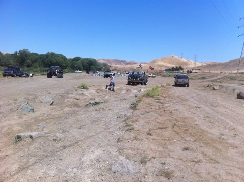 1990 Ford Bronco - Several vehicles are present in an off-road area under a clear blue sky.