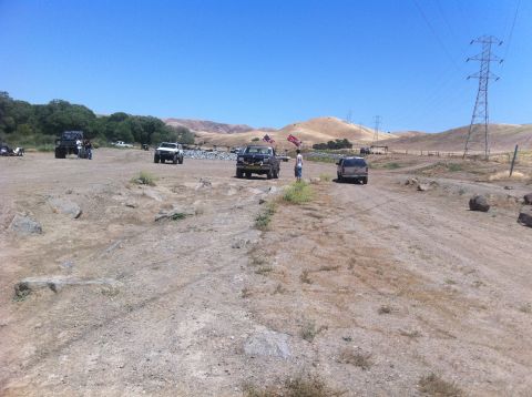 1990 Ford Bronco - Off-road vehicles gather in a dry, open landscape under a clear blue sky.