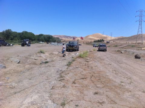 1990 Ford Bronco - Several off-road vehicles are visible on a dirt track under a clear blue sky.