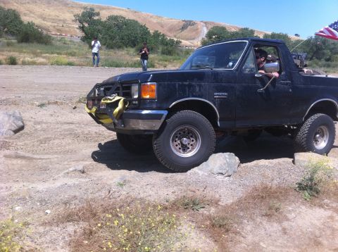1990 Ford Bronco - This Ford Bronco is navigating a rocky trail with an American flag flying from the rear.