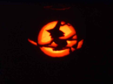1996 Ford Taurus - A carved pumpkin displays a witch silhouette against a glowing orange backdrop.