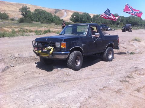 1990 Ford Bronco - Ford Bronco parked off-road with flags flying in the background.