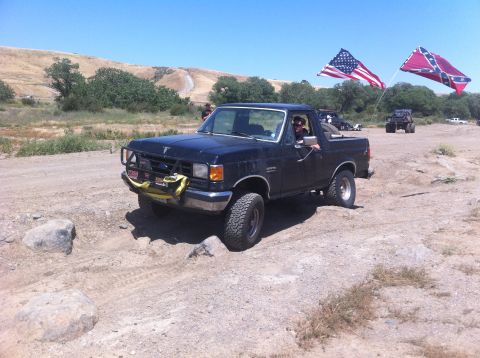 1990 Ford Bronco - 1990 Ford Bronco navigating rough terrain with flags displayed.
