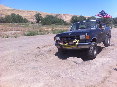 1990 Ford Bronco - This Ford Bronco is navigating a rocky trail under a clear blue sky.