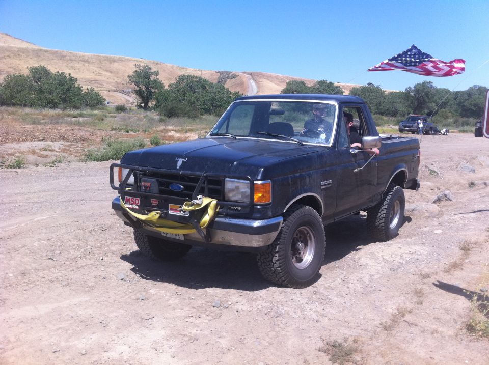1990 Ford Bronco with brush guard and American flag kite flying above