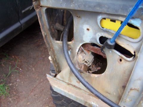 1973 Ford Bronco - Detail of a corroded vehicle body panel, showing wiring and a blue cable, suggesting a need for repair.