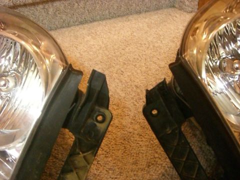 2005 Dodge 3500 - Close-up view of two vehicle headlights, likely for replacement, on a carpeted floor.