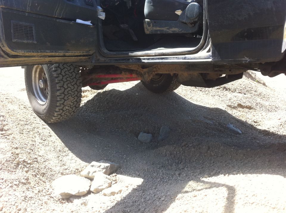 Interior and undercarriage of black SUV with open door, off-road tires
