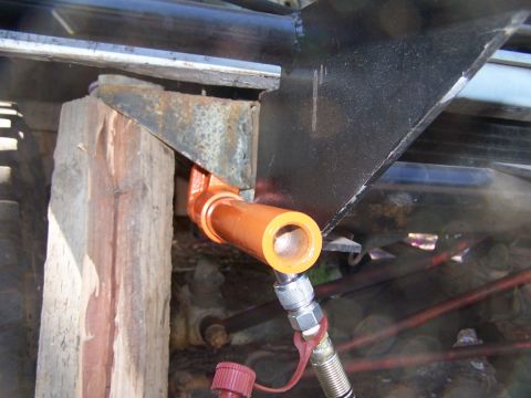 1973 Ford Bronco - Hydraulic line connection to vehicle frame, supported by wood block.