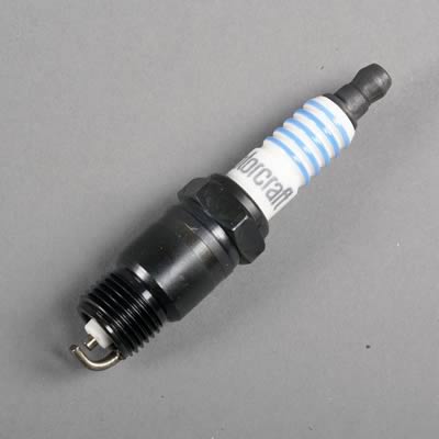 1990 Ford Bronco - A Motorcraft spark plug, identifiable by its branding and blue and white striped insulator, is shown against a neutral gray background.