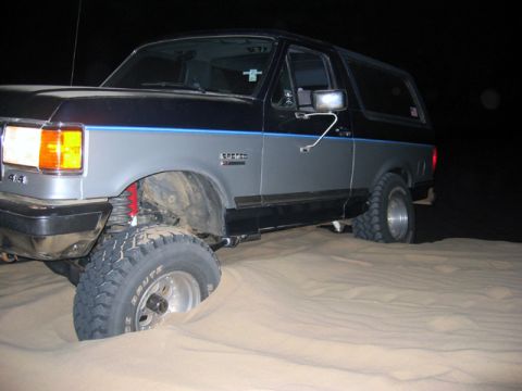 1989 Ford Bronco - This lifted Ford Bronco is stuck in the sand at night.