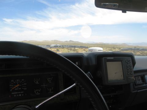 1986 Ford Bronco - Driving through a desert landscape with a GPS unit and gauges visible on the dashboard.
