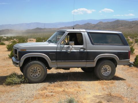 1986 Ford Bronco - This Ford Bronco is parked in a dry, arid environment with mountains in the background.