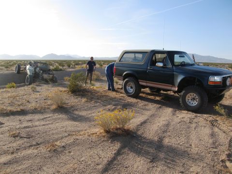 1986 Ford Bronco - Ford Bronco in desert landscape next to an overturned off-road vehicle.