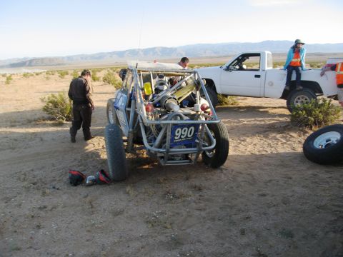 1986 Ford Bronco - An off-road buggy with number 990 is parked next to a white pickup truck in a desert landscape.