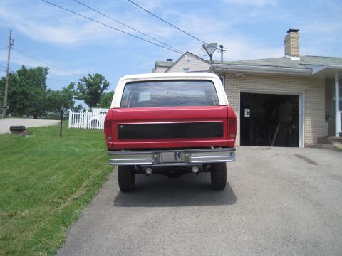 1979 Ford Bronco - Rear view of a red and white Ford Bronco with a chrome bumper and a black panel on the tailgate.