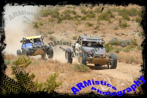 1995 Ford Bronco - Two buggies race through a dusty desert terrain, with one in the foreground and another in the background.