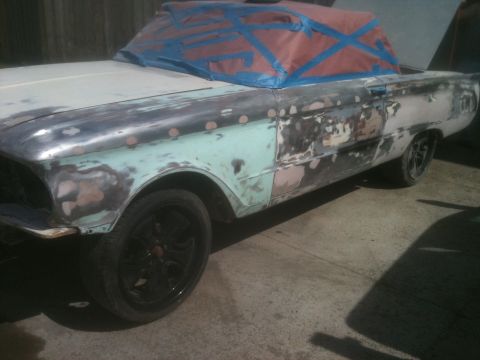 2001 Ford F-350 - A car undergoing bodywork, with its roof covered in protective tape. The vehicle shows signs of rust and repair.