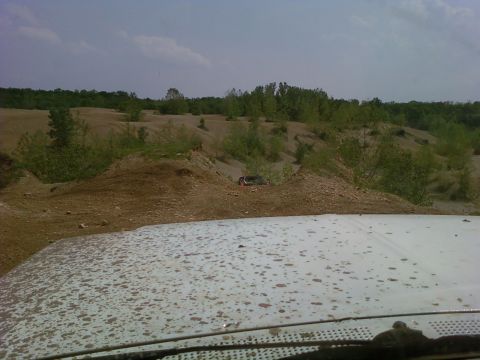 1989 Ford Bronco - A white Ford Bronco navigates a dirt terrain with sparse vegetation under a cloudy sky.