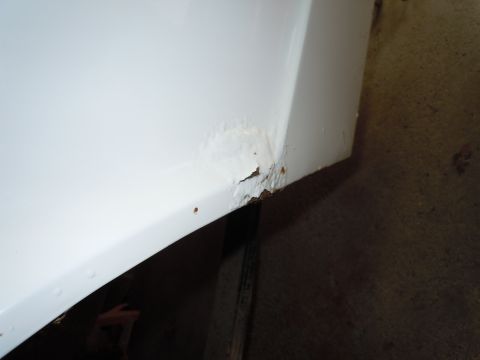 2001 Ford Crown Victoria - Corrosion is evident on the lower section of a white vehicle's body panel.