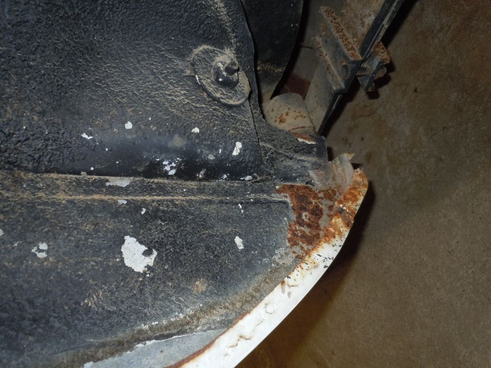Undercarriage of a vehicle with significant rust on the lower body panel and frame