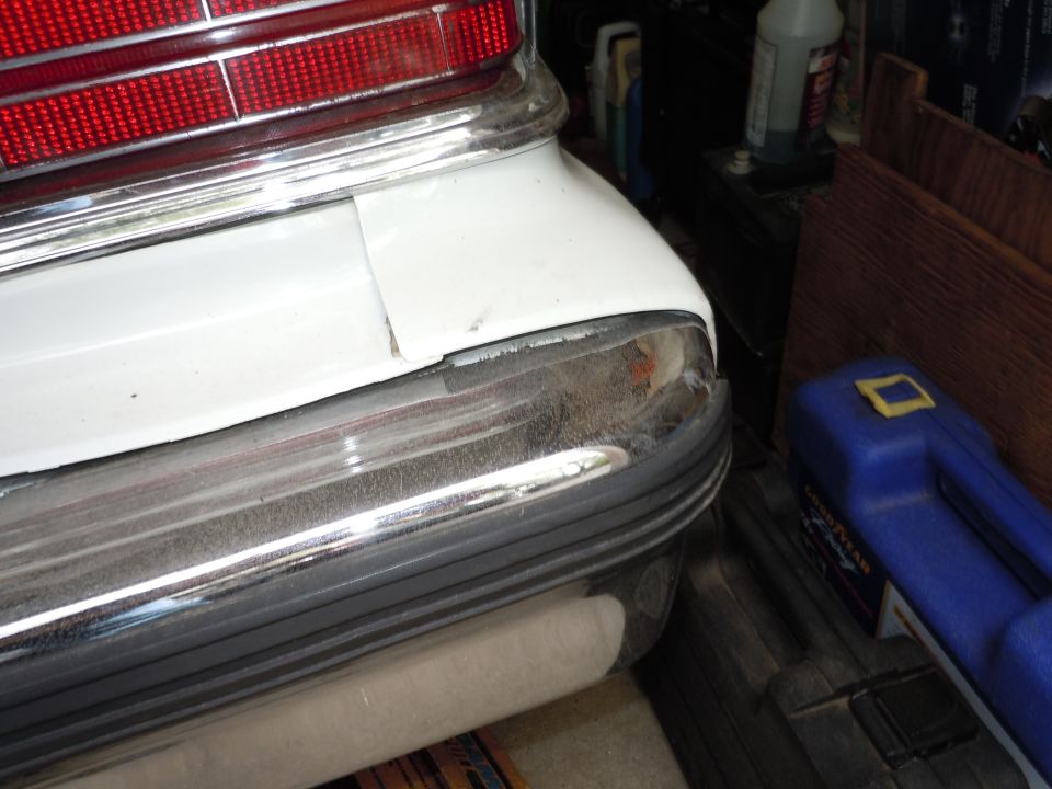 White 2001 Ford Crown Victoria rear bumper with chrome trim and a red taillight. The bumper shows some wear and tear