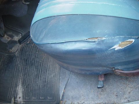 1979 Ford Bronco - The interior of a vehicle shows a damaged seat and a dirty floor mat, with a watermark from Supermotors.net.