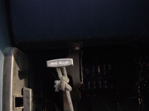 1979 Ford Bronco - The interior of a vehicle shows a brake release lever with a rope attached.